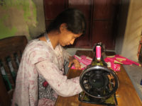 a lady is stiching cloth with sewing machine